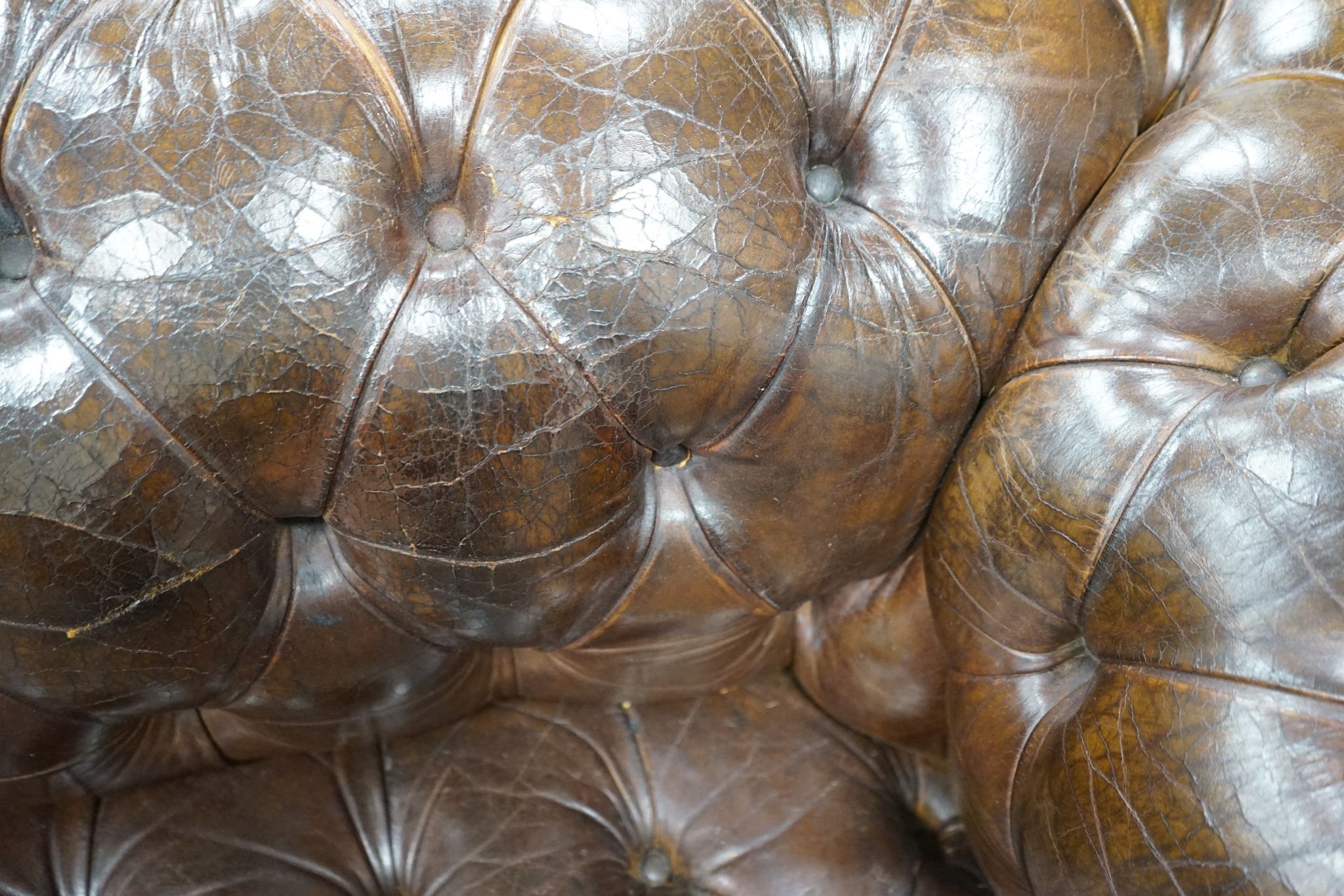 An early 20th century Chesterfield settee upholstered in deep buttoned brown leather, length 200cm, depth 90cm, height 72cm